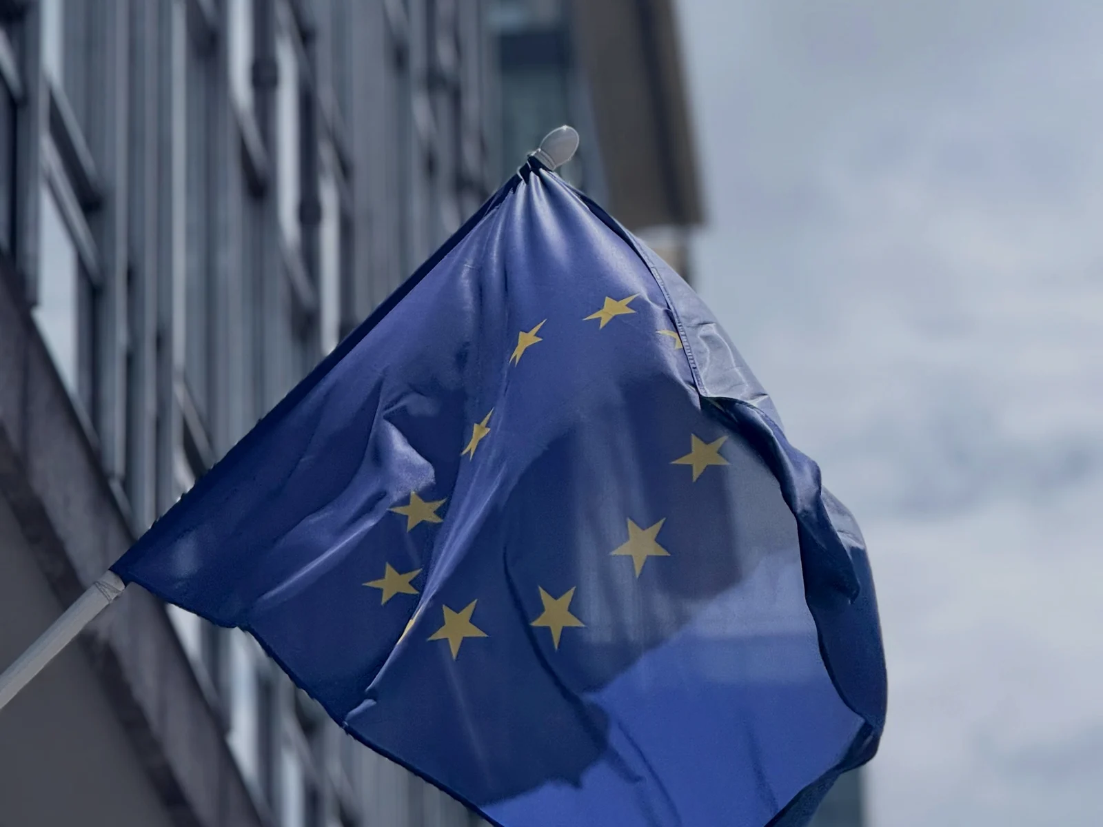 EU-flagga framför en modern myndighetsbyggnad i Bryssel